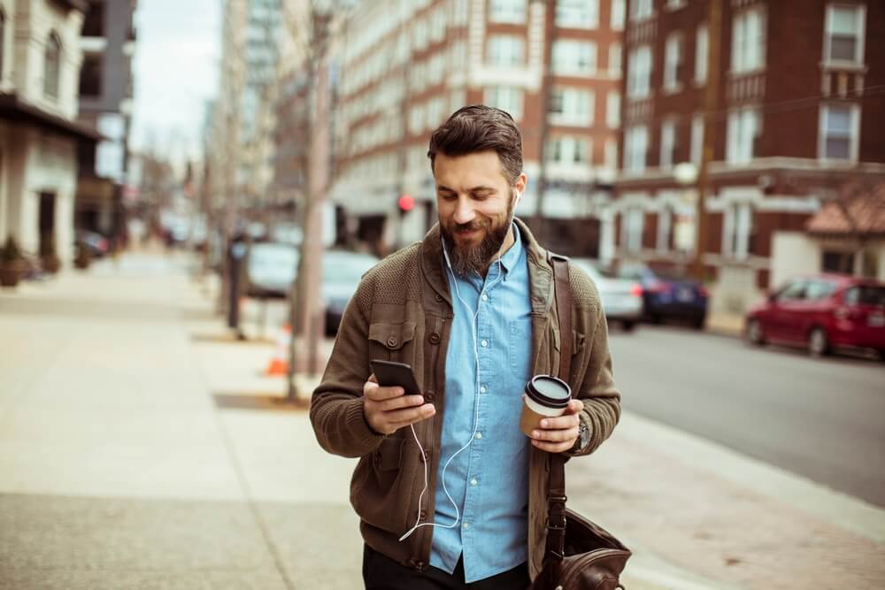 man walking while watching his phone